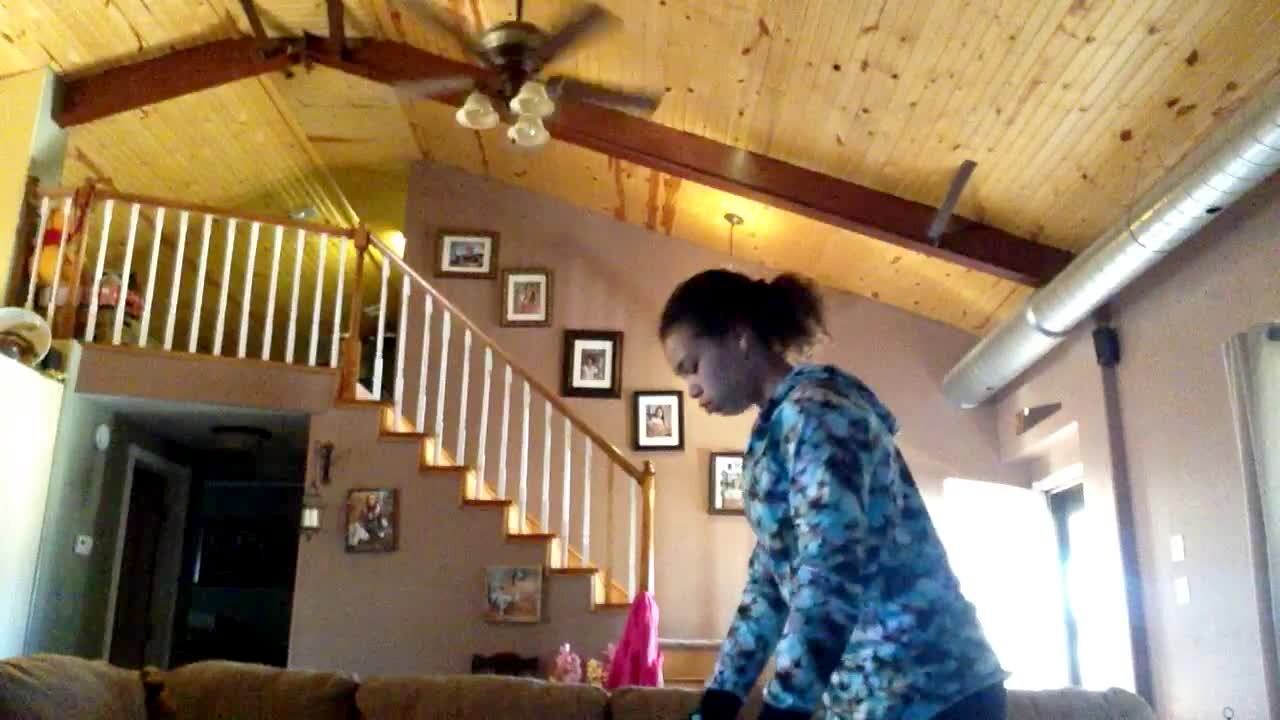Video thumbnail showing: A young girl hits herself in the back of the head with an elastic exercise rope when it slides off of her foot as she stretches in the living room.