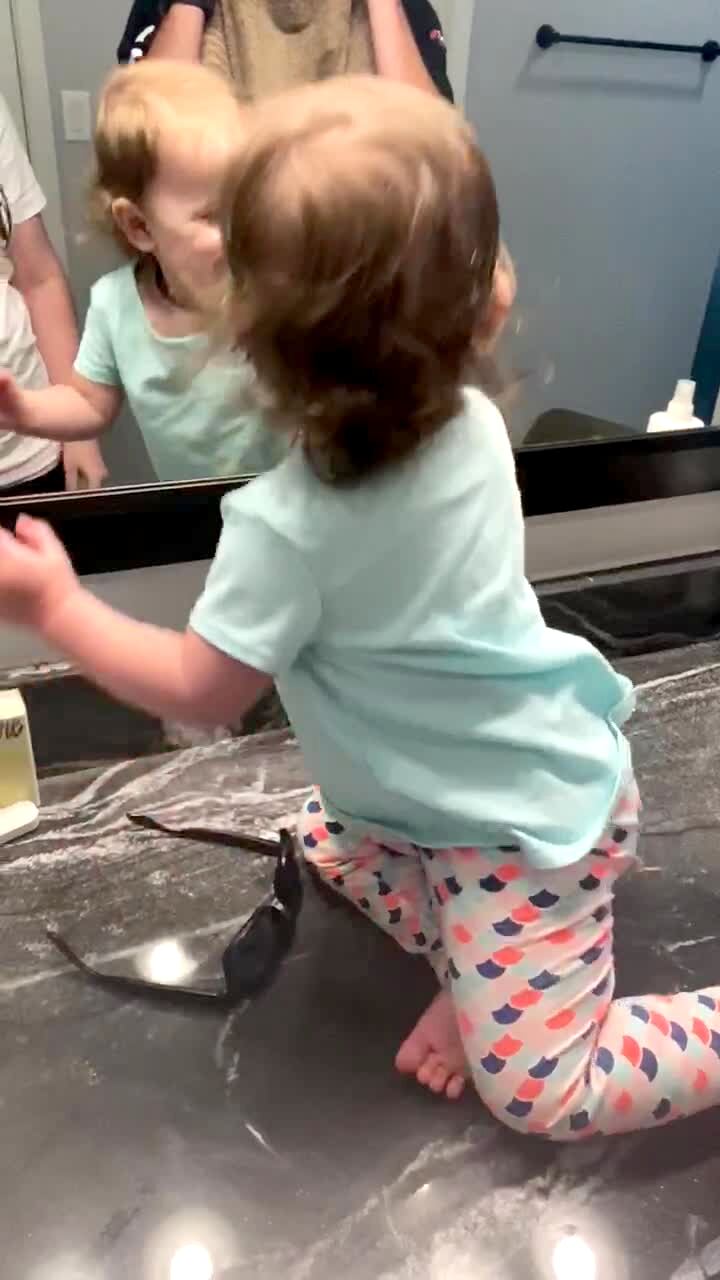 Video thumbnail showing: A man plays peekaboo with his tot girl with a towel over his face and makes her laugh, but  then he pulls the towel down to reveal his beard is gone and she gets sad.